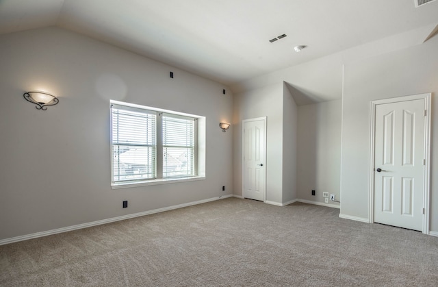 empty room featuring vaulted ceiling and light colored carpet