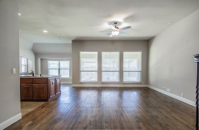 unfurnished living room with ceiling fan, sink, dark hardwood / wood-style floors, and vaulted ceiling