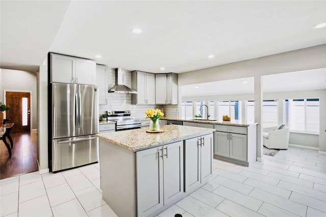 kitchen featuring wall chimney range hood, a center island, appliances with stainless steel finishes, and sink