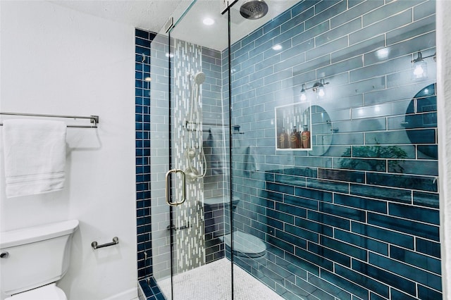 bathroom featuring a shower with shower door and toilet