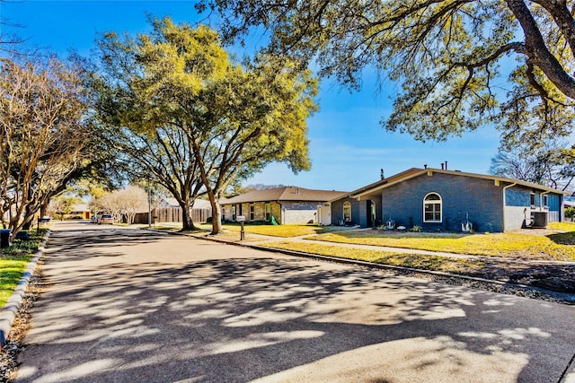 single story home featuring central AC unit and a front lawn