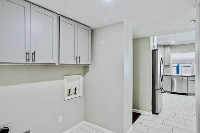 washroom with light tile patterned flooring, cabinets, and washer hookup