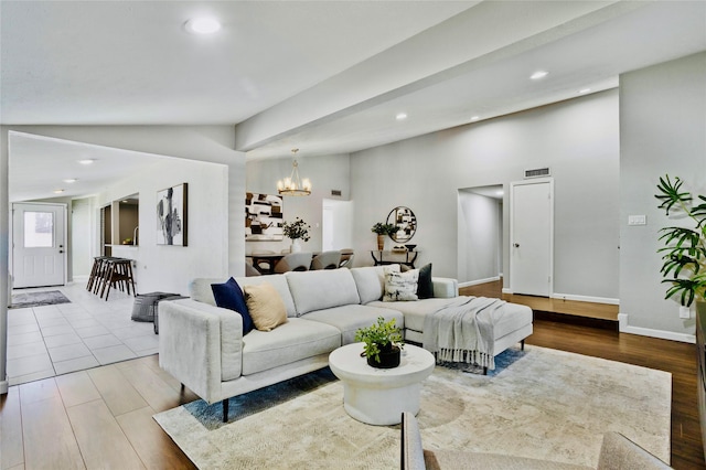 living room with light hardwood / wood-style floors, vaulted ceiling, and an inviting chandelier