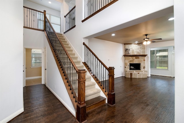 stairs with a fireplace, hardwood / wood-style floors, and ceiling fan