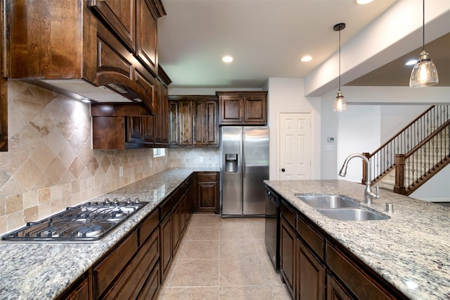 kitchen with sink, decorative light fixtures, light stone countertops, and appliances with stainless steel finishes