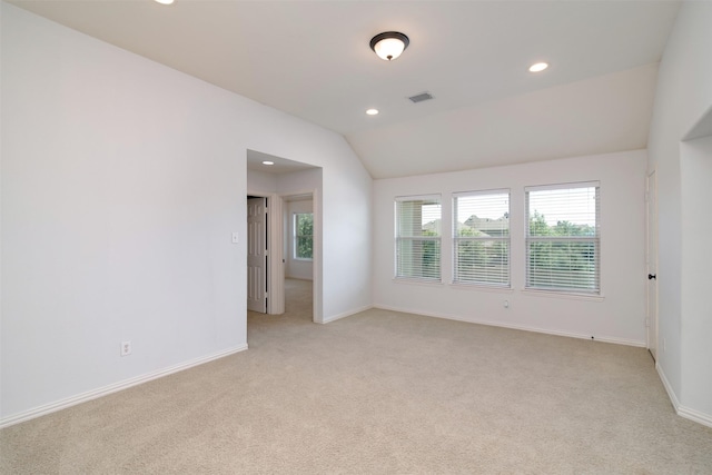 carpeted empty room featuring vaulted ceiling