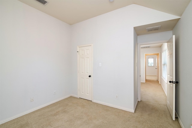 carpeted spare room with vaulted ceiling