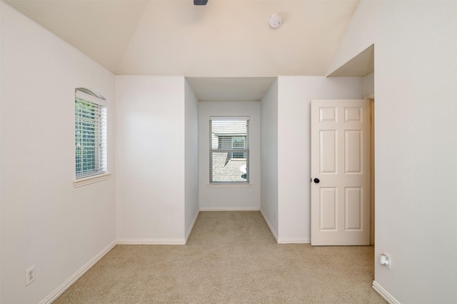 carpeted empty room with a healthy amount of sunlight and lofted ceiling