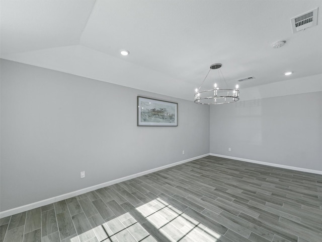 spare room with lofted ceiling, hardwood / wood-style floors, and a notable chandelier