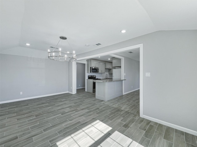 kitchen featuring pendant lighting, appliances with stainless steel finishes, lofted ceiling, and an inviting chandelier