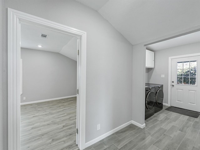 laundry area with light hardwood / wood-style floors, cabinets, and washing machine and dryer