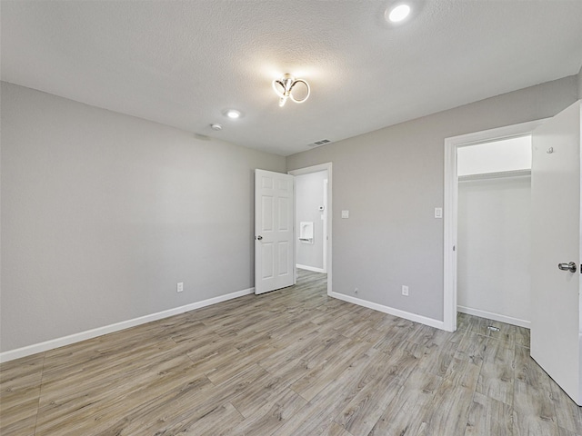 unfurnished bedroom with a textured ceiling, a closet, and light hardwood / wood-style flooring