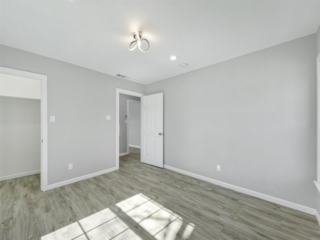 unfurnished bedroom featuring a closet, a walk in closet, and light hardwood / wood-style flooring