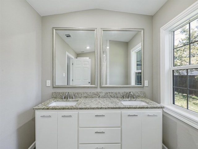 bathroom with vaulted ceiling, a wealth of natural light, and vanity