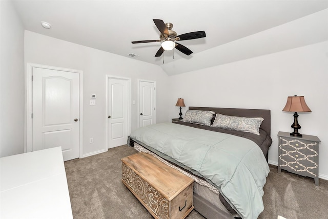 bedroom with multiple closets, dark colored carpet, vaulted ceiling, and ceiling fan