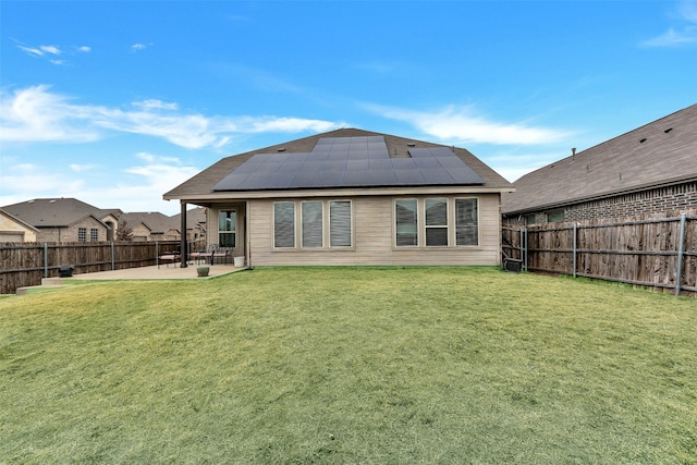 rear view of house featuring a lawn, a patio, and solar panels