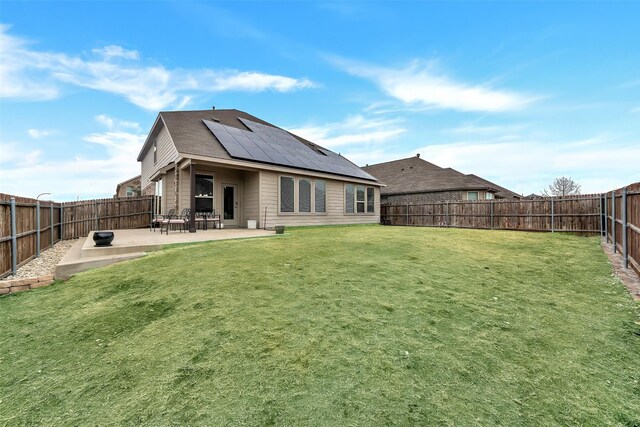 back of house featuring a yard, a patio area, and solar panels