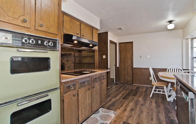 kitchen featuring dark wood-type flooring, dishwasher, double oven, black electric stovetop, and a textured ceiling