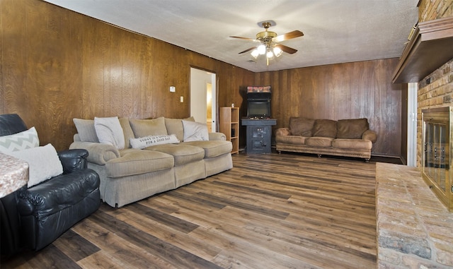 living room featuring ceiling fan, wooden walls, a fireplace, and dark hardwood / wood-style flooring