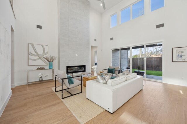 living room featuring light hardwood / wood-style floors, a high ceiling, sink, and a fireplace