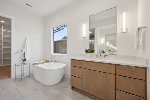 bathroom featuring vanity, a washtub, and tile patterned flooring