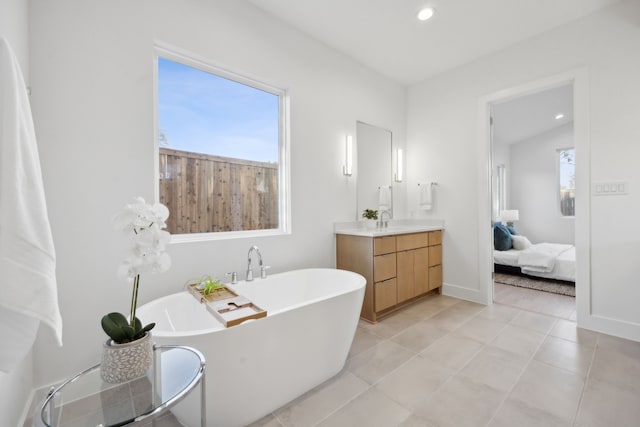 ensuite bathroom featuring ensuite bath, a freestanding bath, a wealth of natural light, and vanity