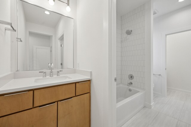 bathroom with tiled shower / bath combo, tile patterned flooring, and vanity