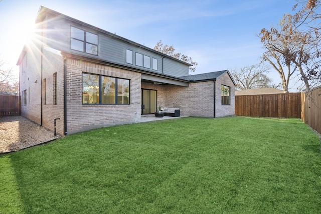 rear view of property featuring brick siding, a lawn, and a fenced backyard