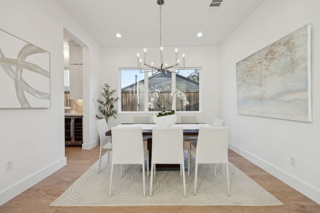 dining space featuring light wood-type flooring, a notable chandelier, and wine cooler