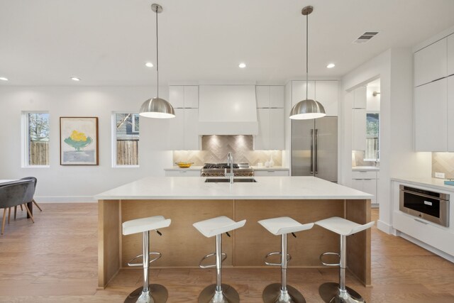 kitchen with hanging light fixtures, a large island, white cabinets, sink, and stainless steel appliances