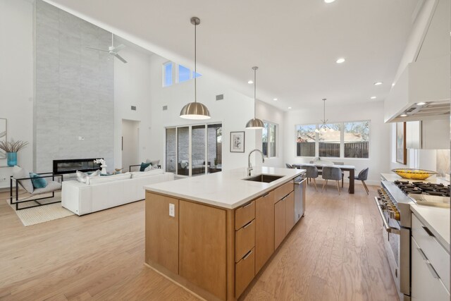 kitchen with sink, stainless steel appliances, white cabinetry, and decorative light fixtures