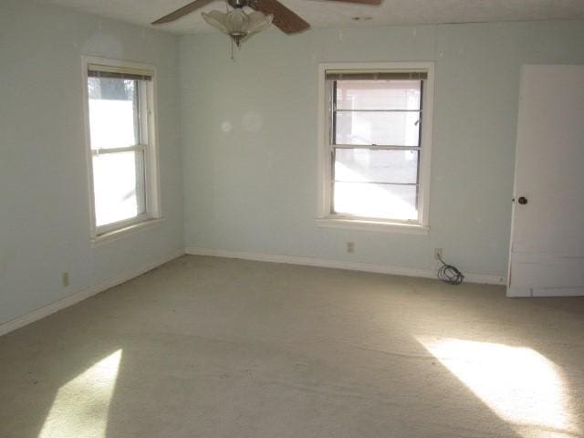 spare room featuring ceiling fan, plenty of natural light, and light carpet