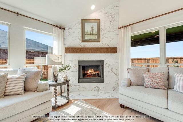 living room with light hardwood / wood-style floors, lofted ceiling, and a premium fireplace