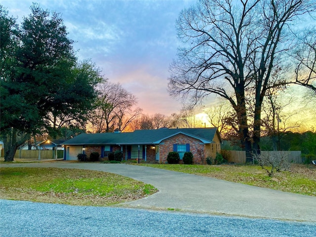 single story home featuring a garage and a lawn