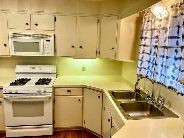 kitchen with sink, white appliances, and cream cabinets