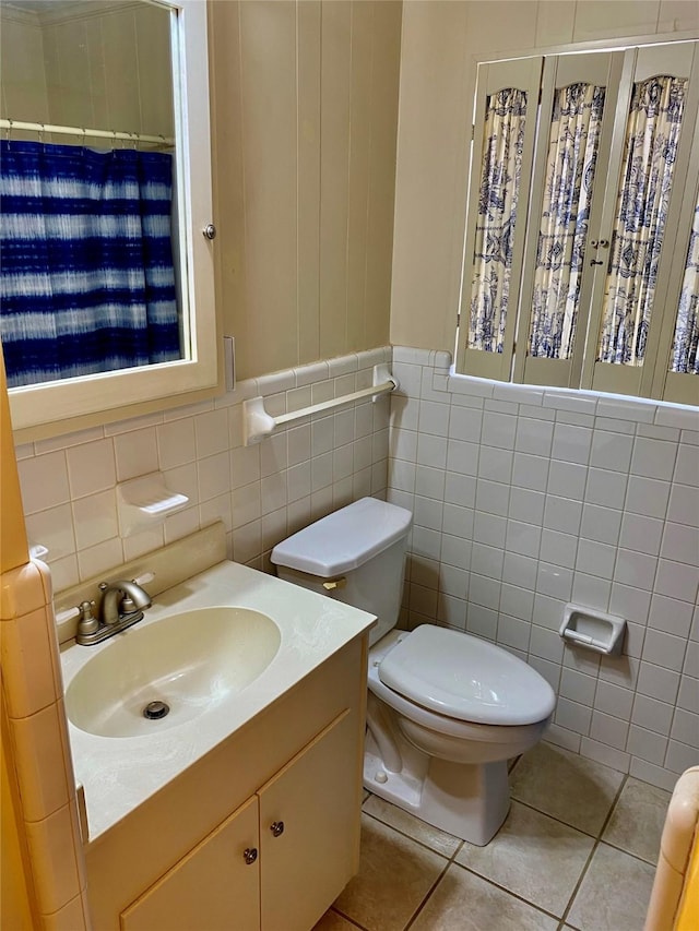 bathroom featuring vanity, toilet, tile patterned floors, and tile walls