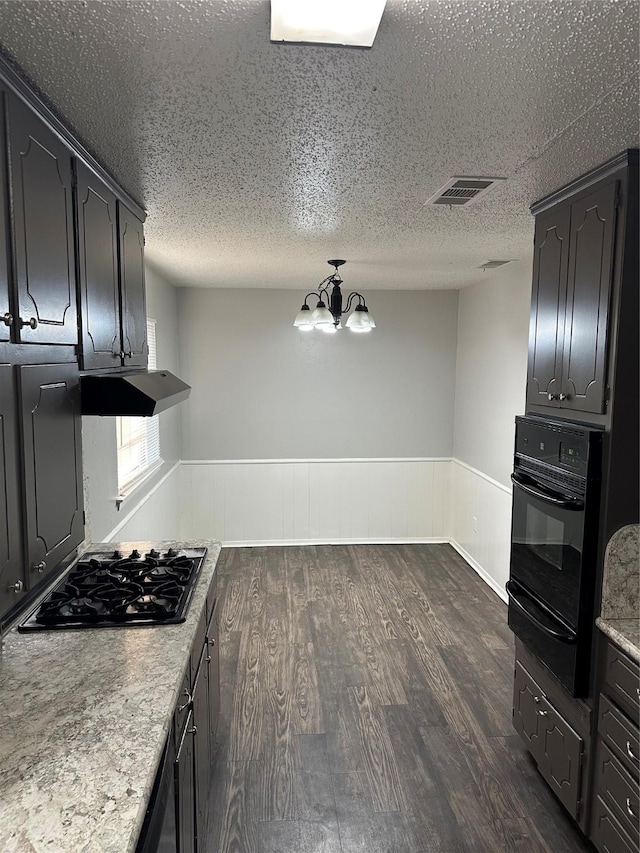 kitchen with an inviting chandelier, dark wood-type flooring, a textured ceiling, and black appliances