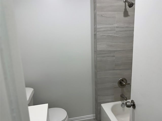 bathroom featuring tiled shower / bath combo and toilet