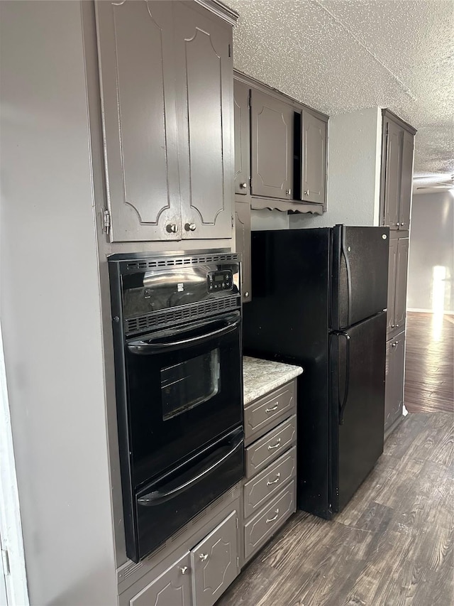 kitchen with dark wood-type flooring, black appliances, a textured ceiling, and gray cabinets