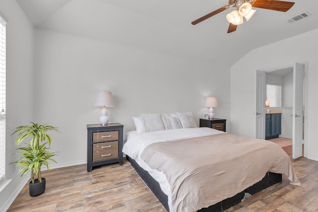 bedroom featuring lofted ceiling, light hardwood / wood-style flooring, connected bathroom, and ceiling fan