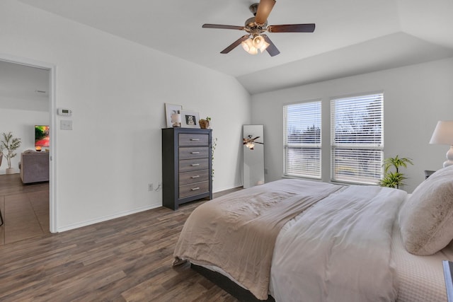 bedroom with ceiling fan, vaulted ceiling, and dark hardwood / wood-style flooring