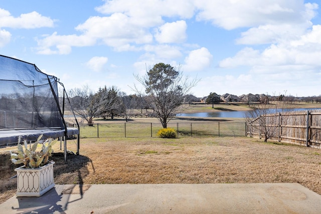 view of yard featuring a patio, a water view, and a trampoline