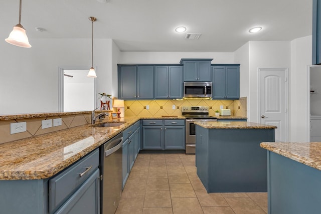 kitchen featuring kitchen peninsula, pendant lighting, sink, blue cabinets, and stainless steel appliances