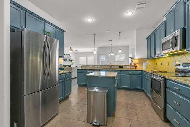 kitchen featuring blue cabinetry, appliances with stainless steel finishes, decorative light fixtures, a kitchen island, and kitchen peninsula