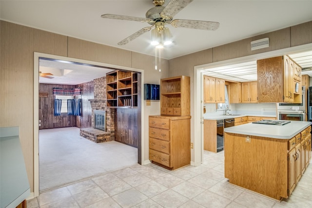 kitchen with light carpet, sink, a fireplace, and ceiling fan