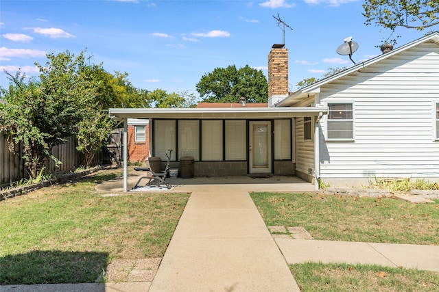 view of exterior entry featuring a patio area and a yard