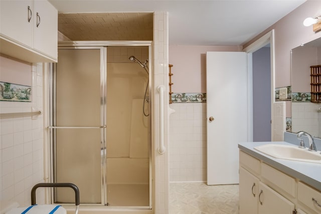 bathroom with tile walls, an enclosed shower, and vanity