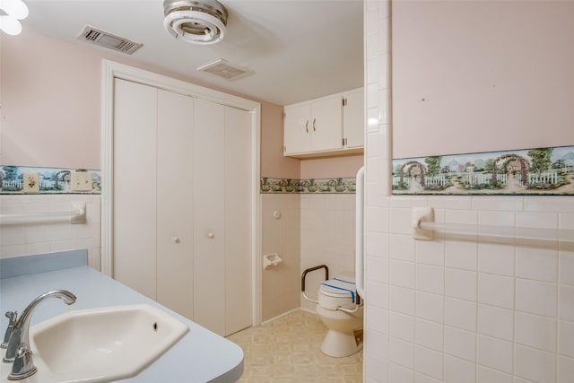 bathroom featuring sink, tile walls, and toilet