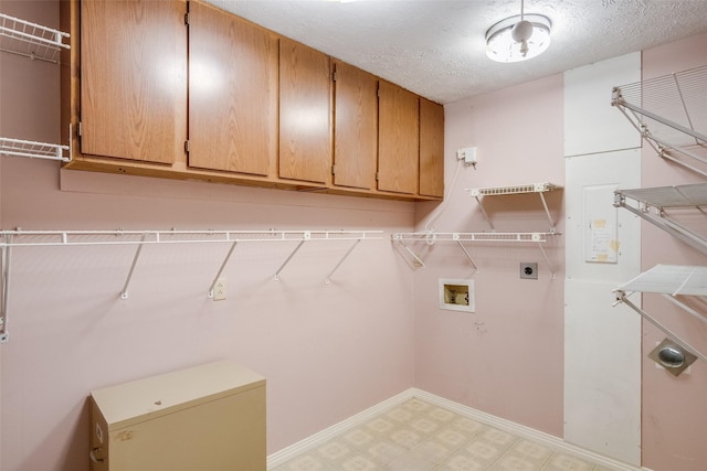 clothes washing area with a textured ceiling, electric dryer hookup, cabinets, and washer hookup