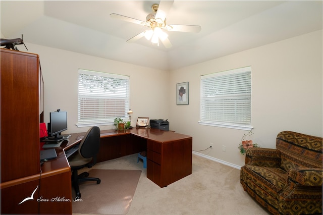 office area featuring light colored carpet, vaulted ceiling, ceiling fan, and a raised ceiling